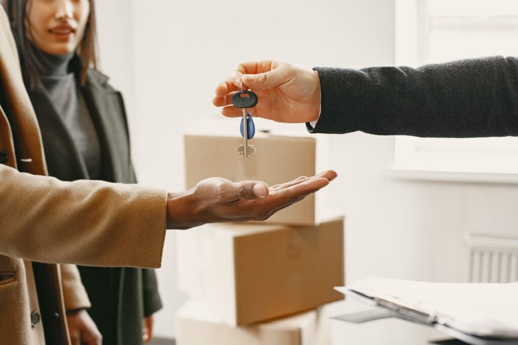 Real estate agent handing over property keys to new homeowners with moving boxes in the background, representing a UAE property handover