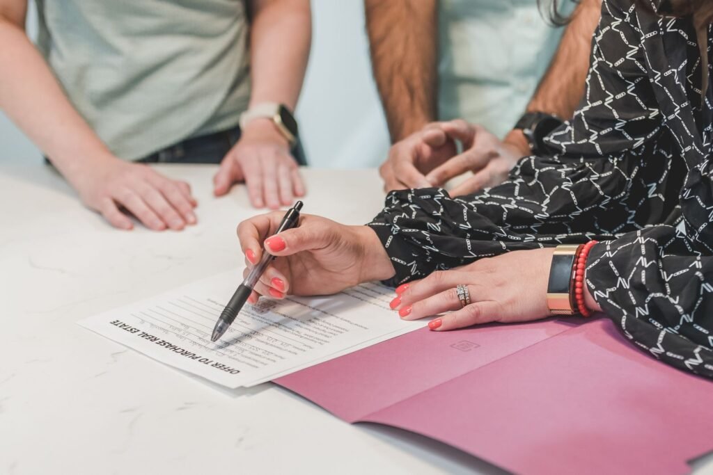 Family signing a real estate offer to purchase document at a table, representing the heir transfer and estate paperwork process for a mortgaged property in the UAE