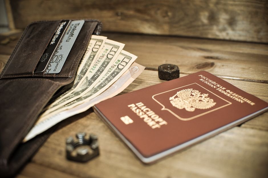 Wallet with US dollar cash, a bank card, and a Russian passport on a wooden table, symbolizing the cash-vs-mortgage-financing decision for Russian buyers in Dubai