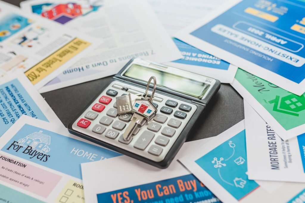Calculator with a house-shaped key resting on mortgage and home-buying brochures, the repayment maths behind choosing a 15, 20 or 25 year UAE mortgage term