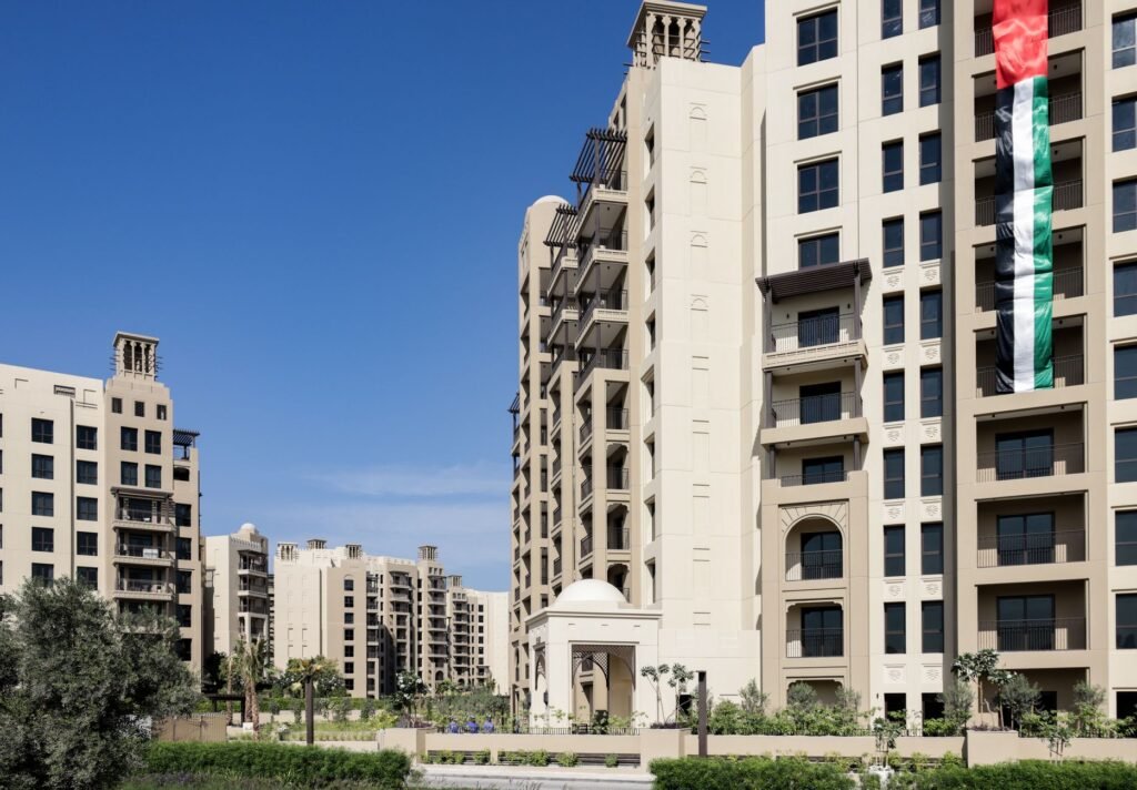 Residential apartment towers in a Dubai community with a UAE flag on a sunny day, the kind of property buyers finance with cash or a mortgage