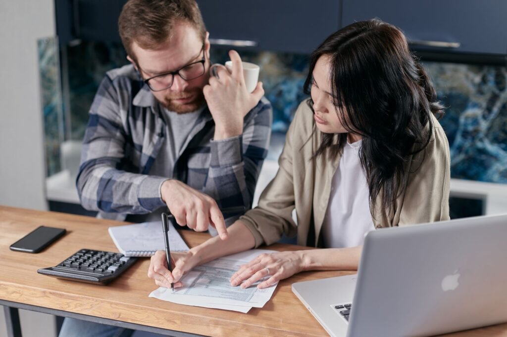 Couple at a table working through household finances with a calculator, laptop and documents, the income and debt check behind a UAE mortgage salary requirement