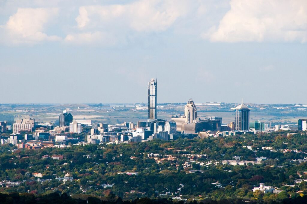 Skyline of Sandton, Johannesburg, with high-rise towers rising above tree-covered suburbs under a blue sky, representing South African expats and buyers financing a Dubai property