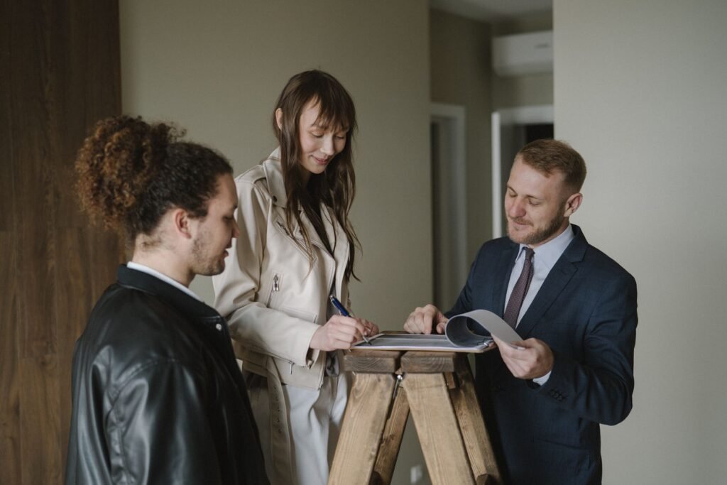 A couple signing property purchase documents with a real estate agent inside a new apartment, representing the contract behind a Dubai payment plan or mortgage